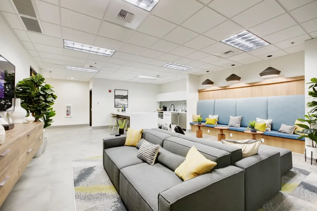 Clubhouse lounge with sofas, TV, kitchenette, and bar height seating