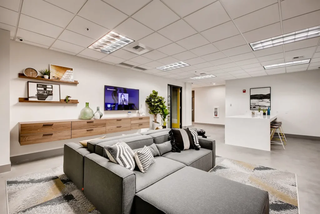 Clubhouse lounge with sofas, TV, kitchenette, and bar height seating