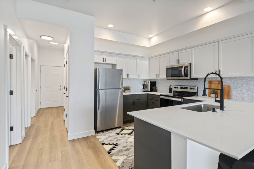 A modern kitchen featuring stainless steel appliances: refrigerator, microwave, stove, and sink. The kitchen has a clean and bright feel. Stainless steel appliances and renovated kitchen